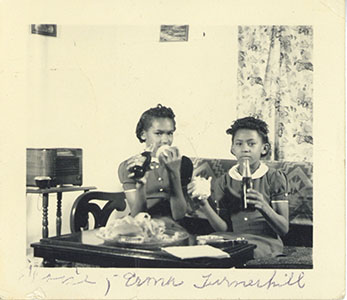 Two young African American girls drinking cokes, circa 1950s
